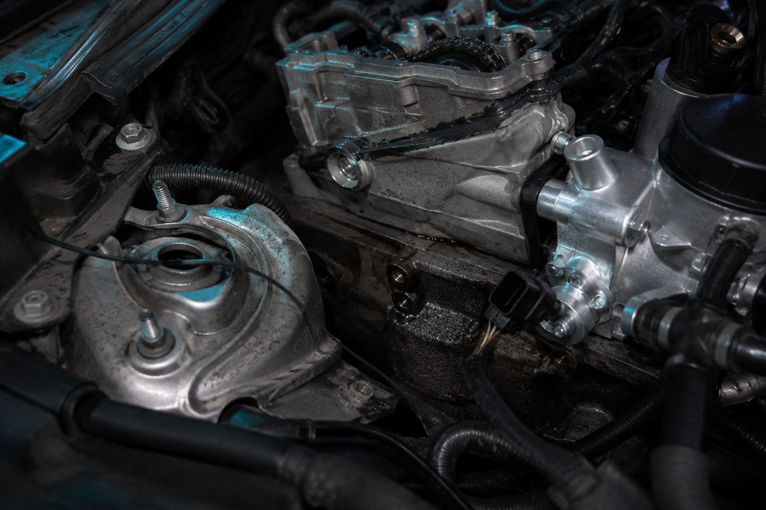 Teilzerlegter Motorraum mit frischen Montagespuren, Dichtmasse an einer Fügestelle, fabrikneuem Bauteil neben verschmutzten Altteilen und offener Steckverbindung – Befundpunkte der Beweissicherung
